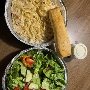 a plate of pasta, salad, and bread