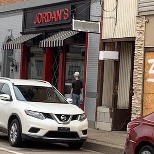 a white nissan suv parked in front of a store
