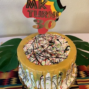 Vanilla cake with buttercream icing and fresh strawberry and banana filling. I asked for paint splatter and paint drip for the design.