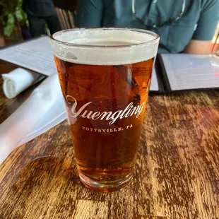 a woman sitting at a table with a glass of beer