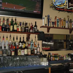 a bar with liquor bottles and a television