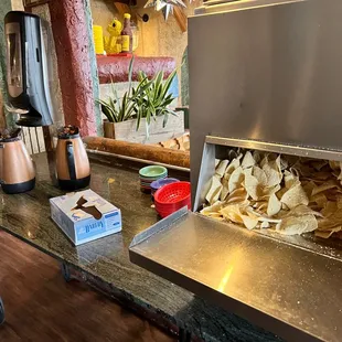 Help yourself to chips and bland salsa. Behind the fireplace.