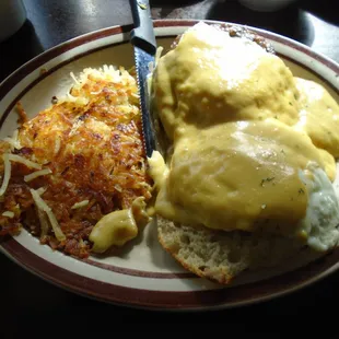 Eggs benedict with sausage and hash browns.