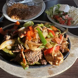 Steak and chicken fajitas with side dishes.