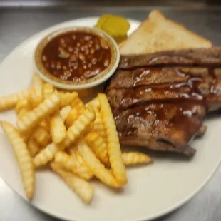 a plate of ribs, french fries and a pickle