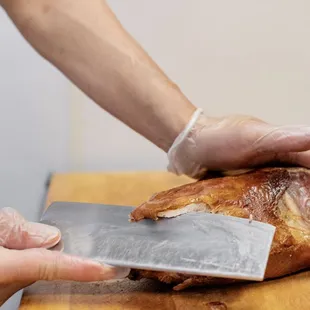 a person slicing a turkey on a cutting board