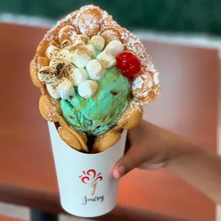 a hand holding a cone of ice - cream