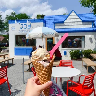 a hand holding a cone of ice cream