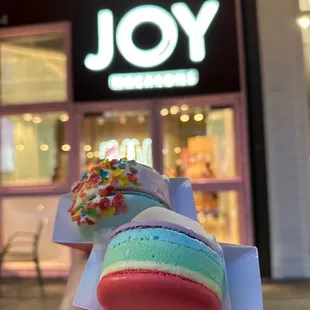 a hand holding a colorful macaron
