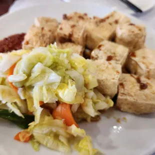 a plate of food with tofu and vegetables