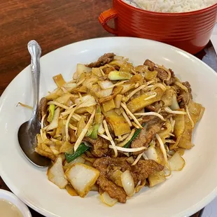 a plate of stir fried noodles with meat and vegetables