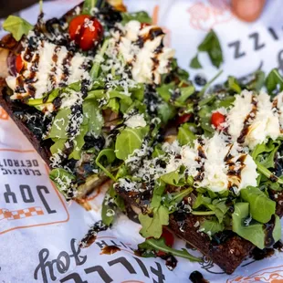 a slice of pizza with greens and tomatoes