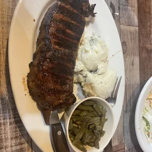 a plate of steak, mashed potatoes, and green beans