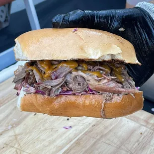 a hand holding a pulled pork sandwich