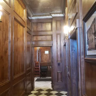 a hallway with wood paneling and a checkered floor