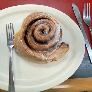Homemade cinnamon roll with lots of cinnamon sugar. Wife has a big smile.