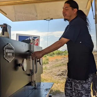 a man filling a beer from a bbq machine