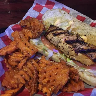 Grilled salmon sandwich with sweet potato fries.