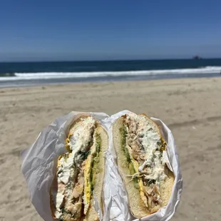 a person holding a sandwich on the beach
