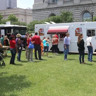 a crowd of people standing in front of a food truck