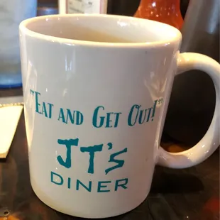 a white coffee mug with tea and get out it's diner written on it
