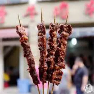 a hand holding a skewer of meat