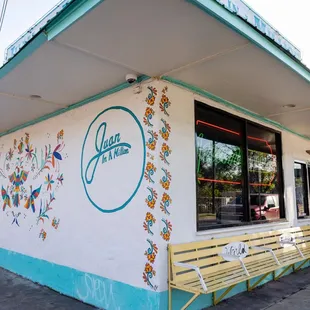 a woman sitting on a bench in front of a restaurant