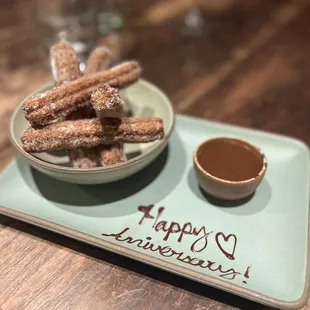 a plate of churros and a bowl of dipping sauce