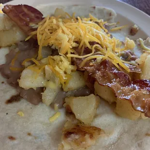 Bacon, bean, potato and cheese taco on flour.