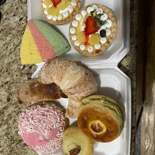a variety of pastries in a styrofoam container