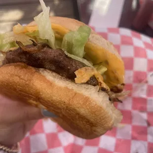 a hand holding a hamburger with lettuce and cheese