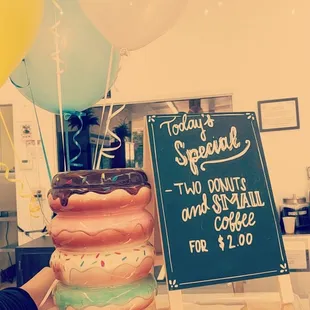 a stack of doughnuts and a coffee sign