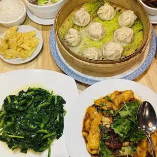 Top left corner clockwise: dan dan noodles, xiao long bao, fish in chili oil and sauteed pea sprouts.