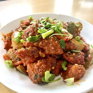 Chili Chicken: Tender chicken pieces stir-fried with bell peppers, onions, and a spicy chili sauce, garnished with green onions.