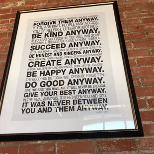 a brick wall with a framed poster on it