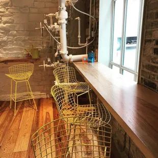 a bar with yellow chairs and a brick wall
