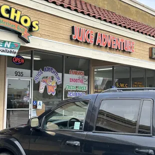 a black suv parked in front of a juice adventure