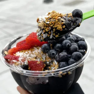 a person holding a spoon full of fruit