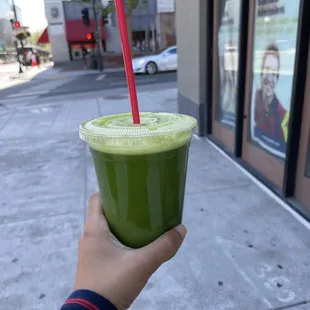 a hand holding a green smoothie