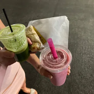 a person holding a drink and a sandwich