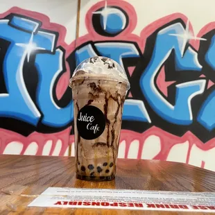 a chocolate milkshake in front of a graffiti wall