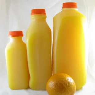 three bottles of orange juice and an orange