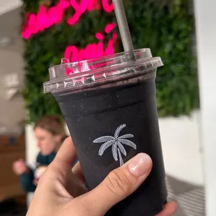 a hand holding a cup with a straw