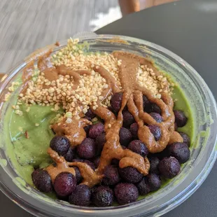 Green bowl with almond butter, frozen blueberries, and quinoa puffs