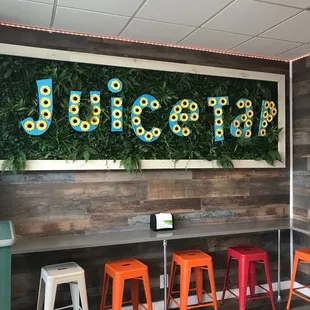 colorful stools in front of a wall of flowers