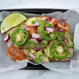a sandwich with avocado, tomatoes, and onions