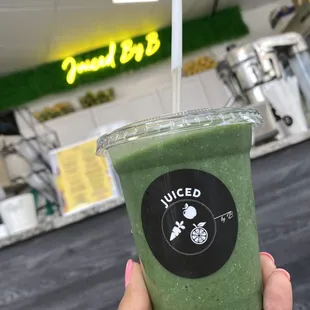 a hand holding a green smoothie