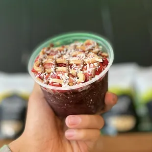 a hand holding a plastic cup filled with fruit and nuts