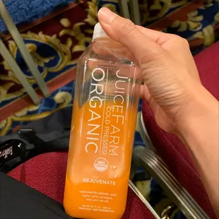 a hand holding a bottle of orange juice