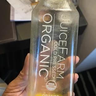 a hand holding a bottle of orange juice